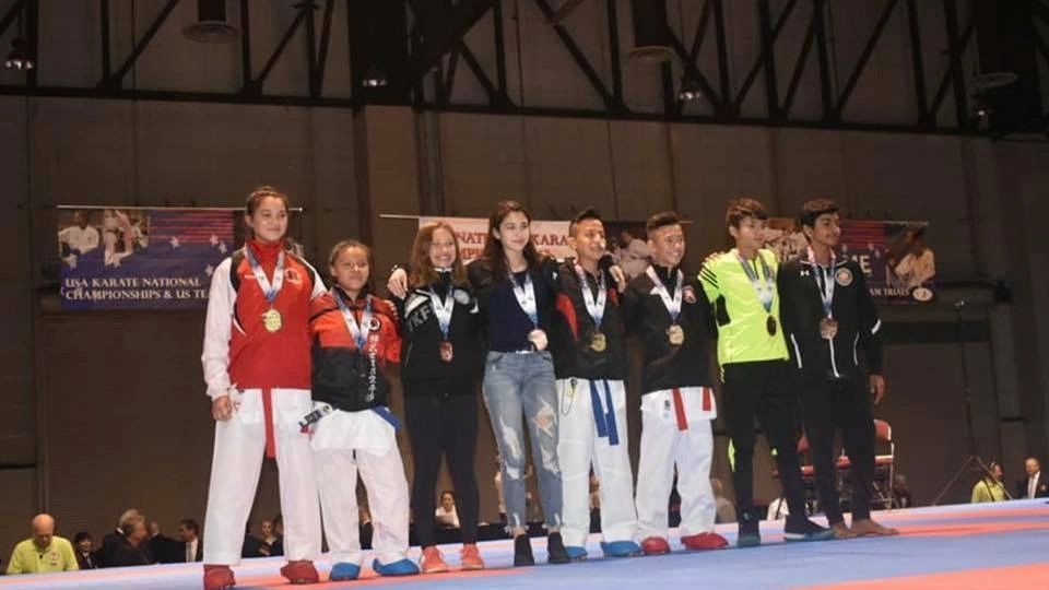 A group of people are standing on a stage with medals around their necks.