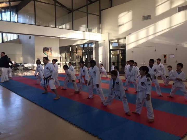 A group of children are practicing martial arts in a gym.