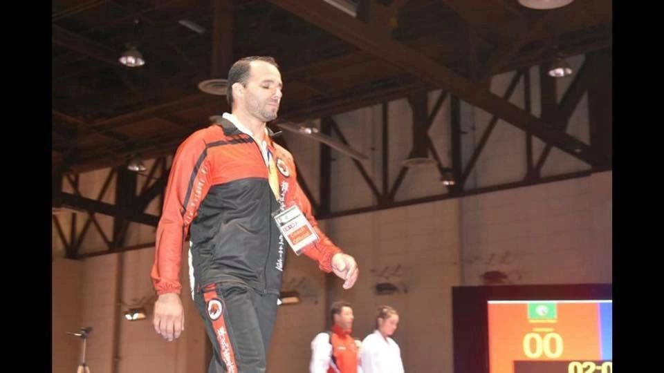 A man in a red and black jacket is walking on a stage