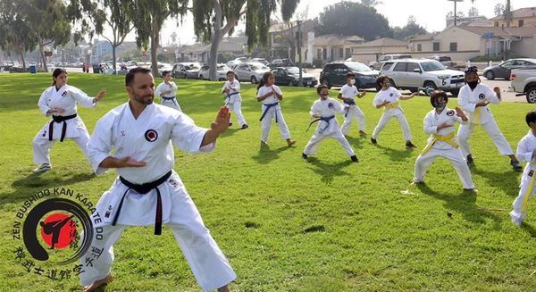 A group of people are practicing karate in a park.