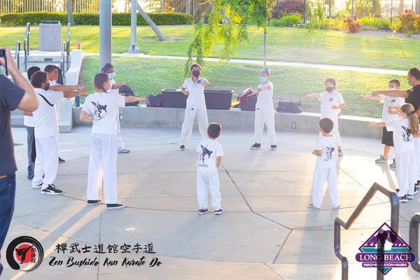 A group of people are practicing martial arts in a park.