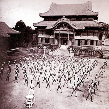 A large group of people are doing exercises in front of a large building