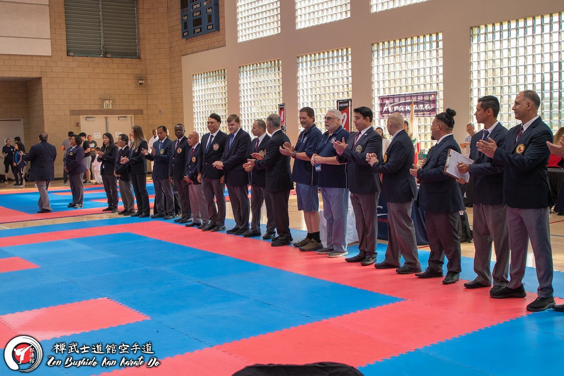 A group of people are standing on a mat in a gym.
