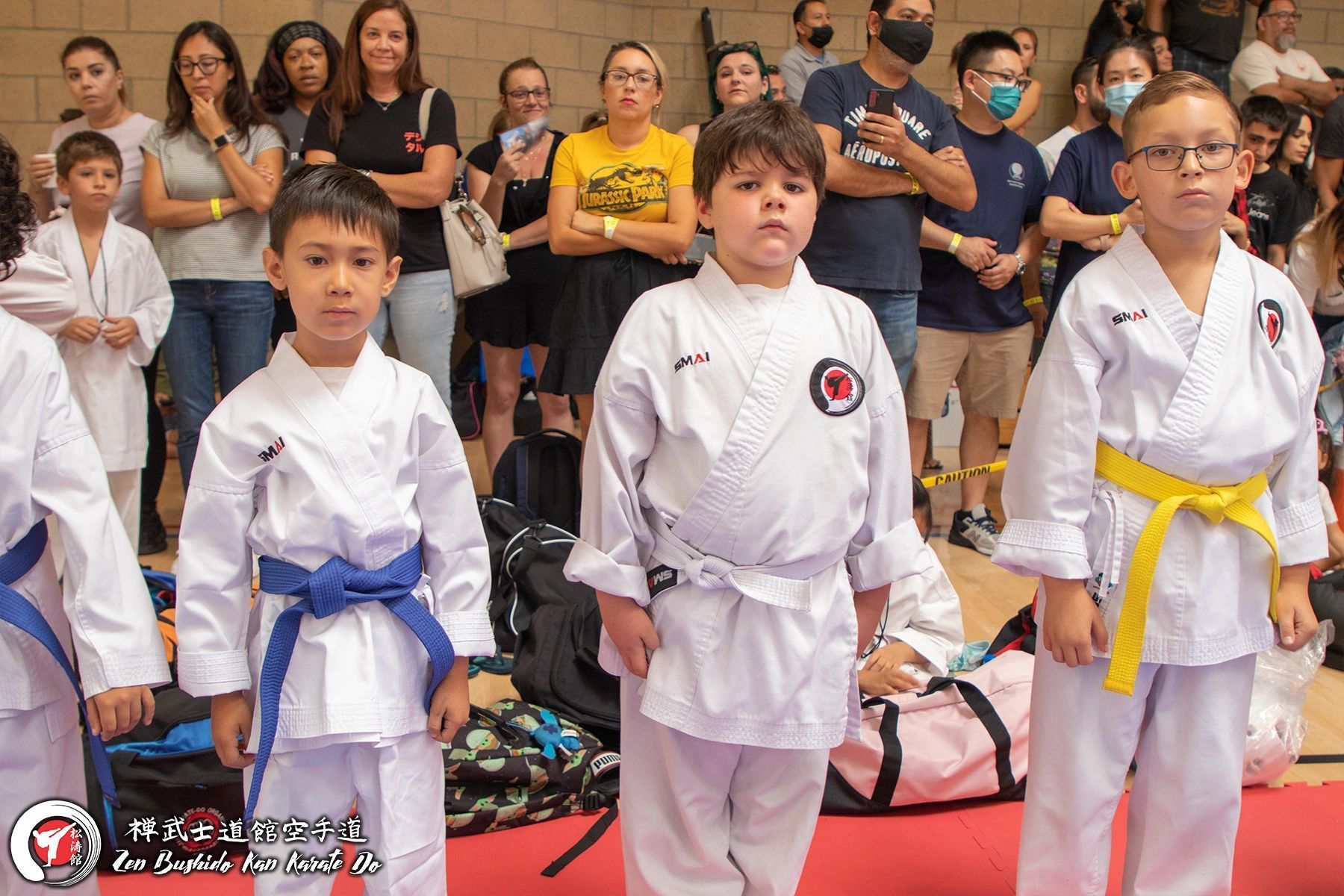 A group of young boys in karate uniforms are standing in front of a crowd.
