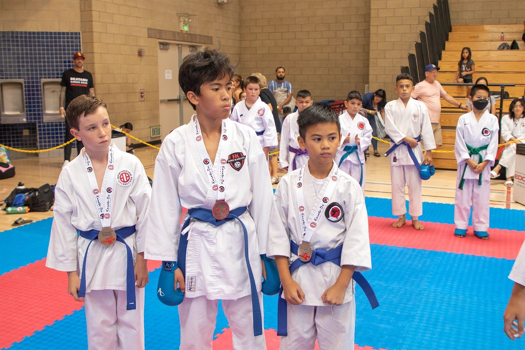 A group of young boys in karate uniforms are standing on a mat in a gym.