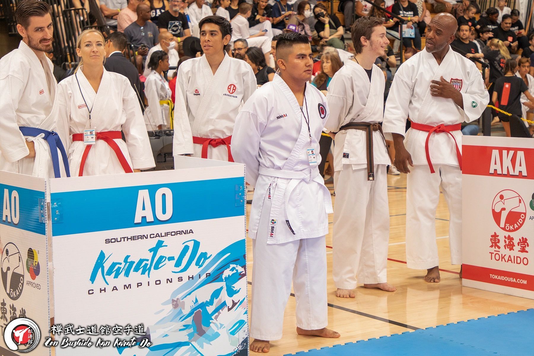 A group of people in karate uniforms are standing next to each other on a basketball court.