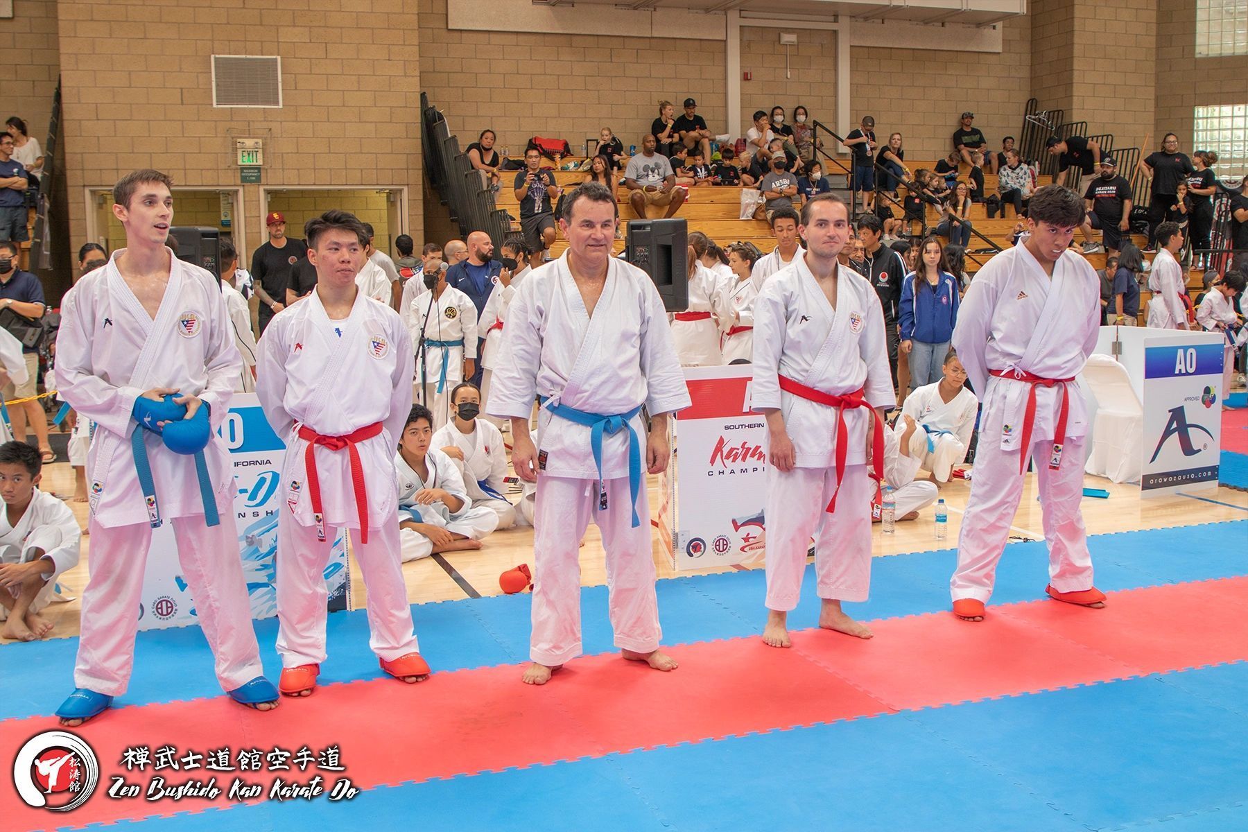 A group of men in karate uniforms are standing on a mat.