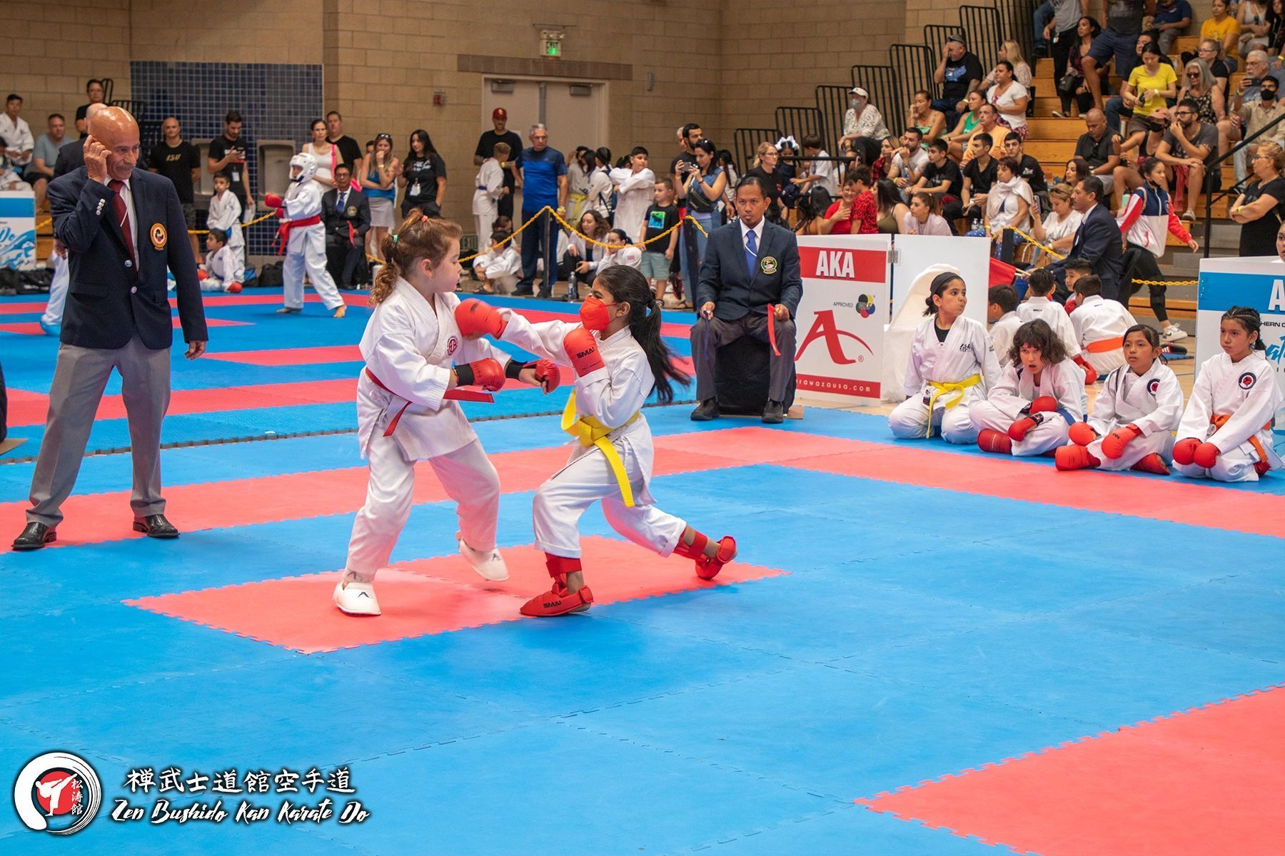 A group of children are playing karate on a mat in a gym.