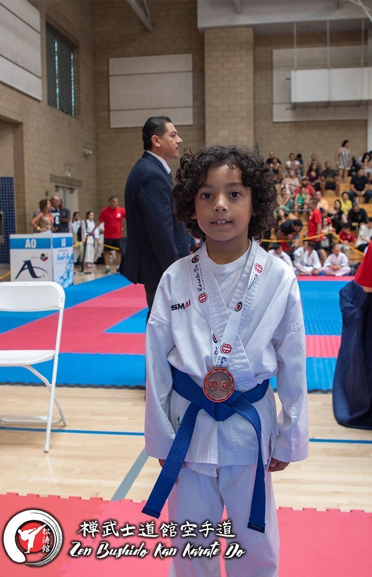A young boy in a karate uniform with a medal around his neck