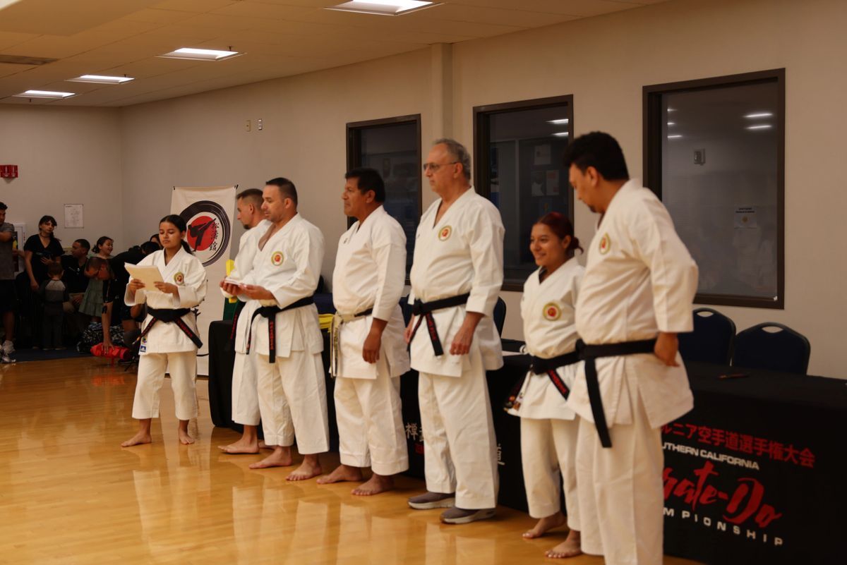 A group of people in karate uniforms are standing in a line in a room.