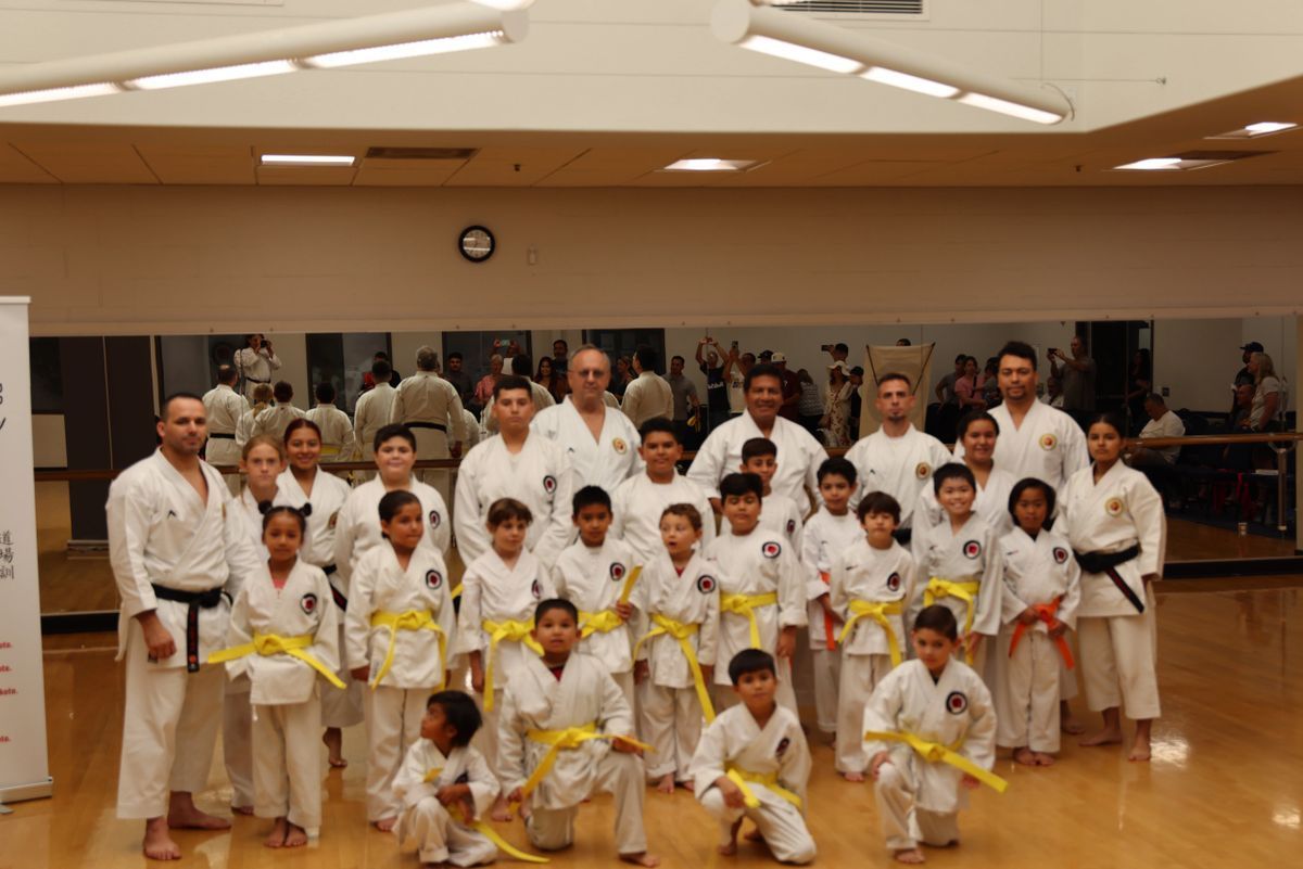 A group of kids in karate uniforms are posing for a picture