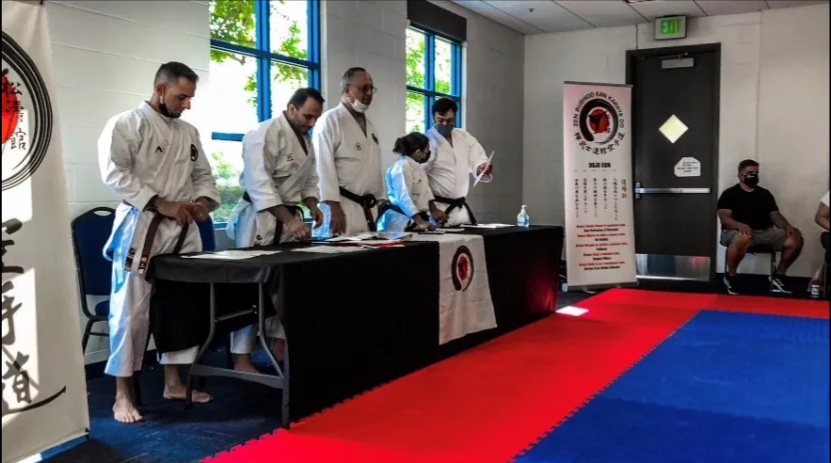A group of people in karate uniforms are standing around a table in a room.
