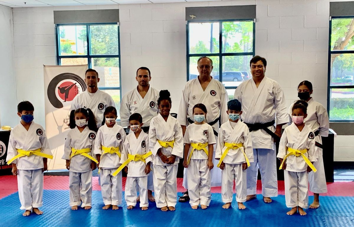 A group of children in karate uniforms are posing for a picture in a gym.