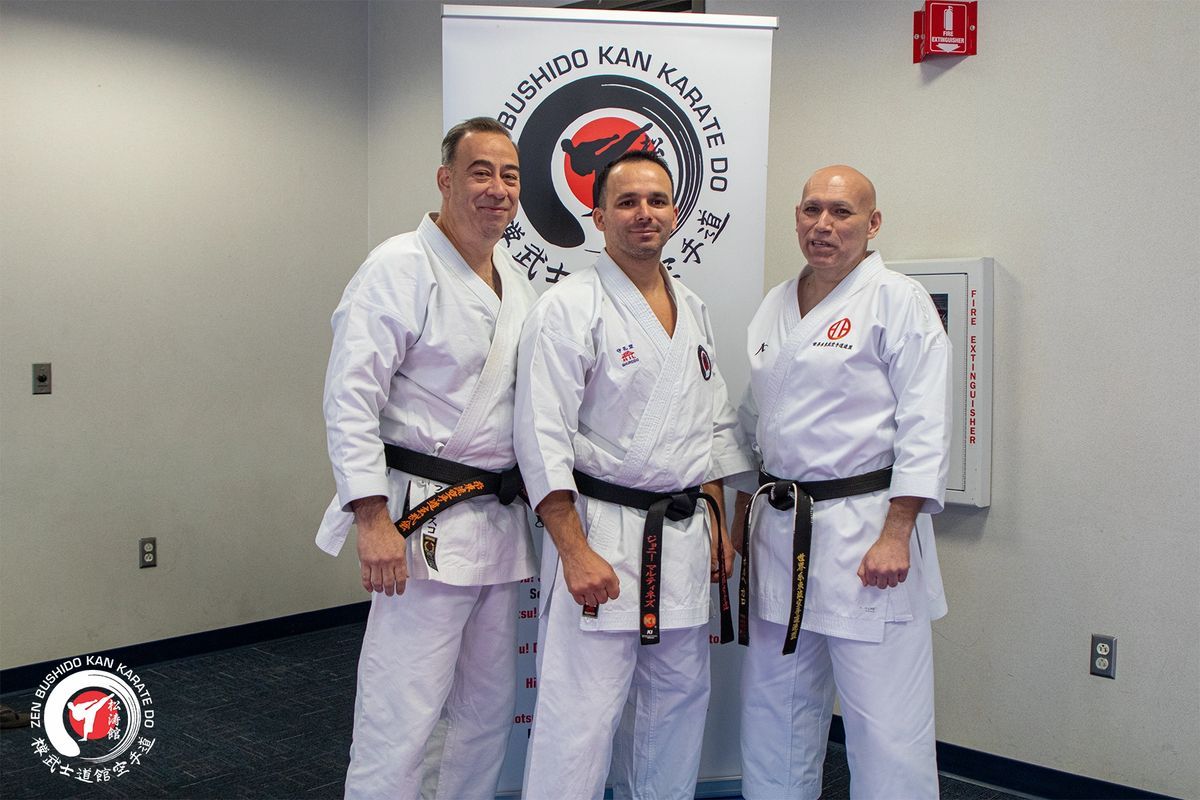 Three men in karate uniforms are posing for a picture in a room.