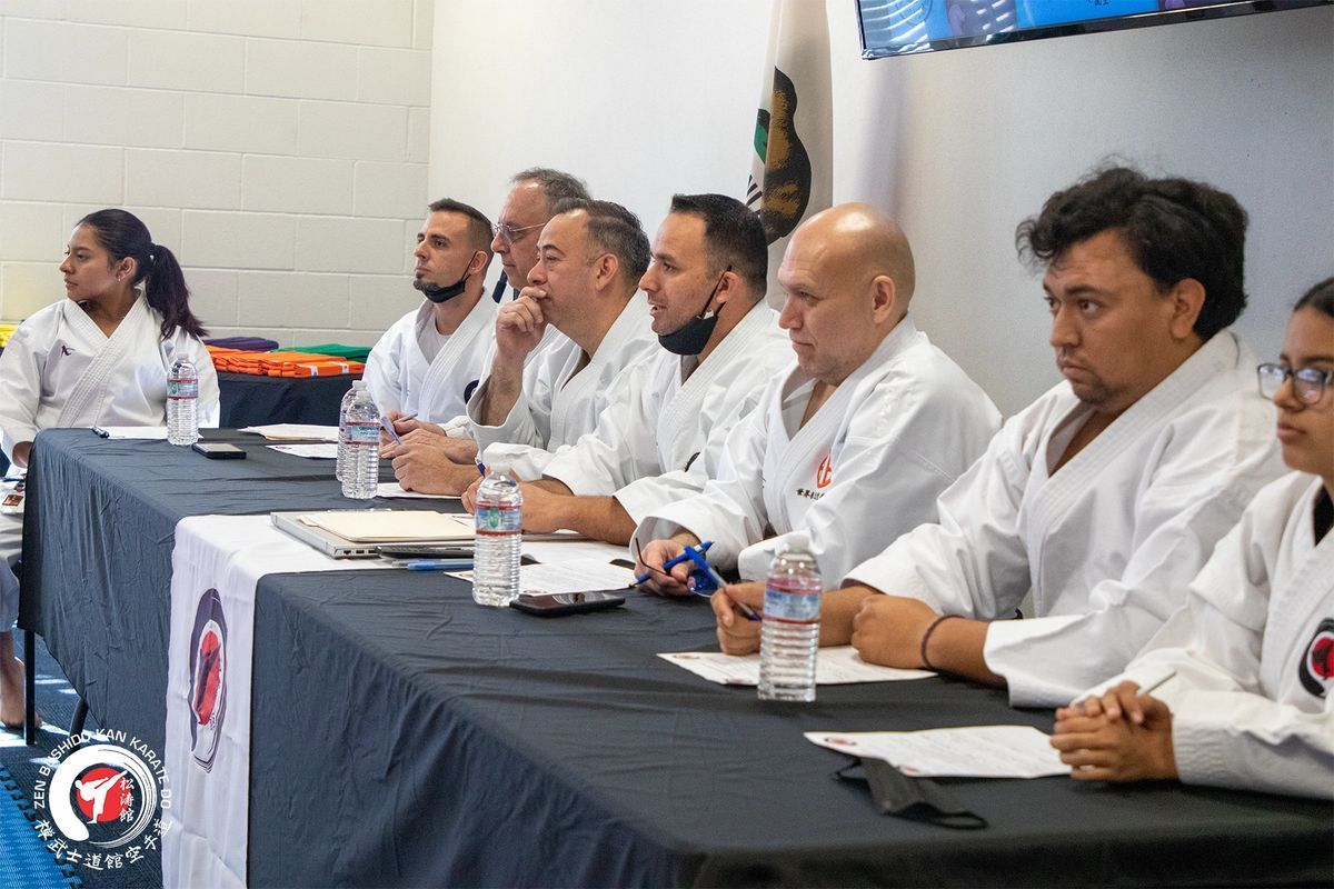 A group of people in karate uniforms are sitting at a table.