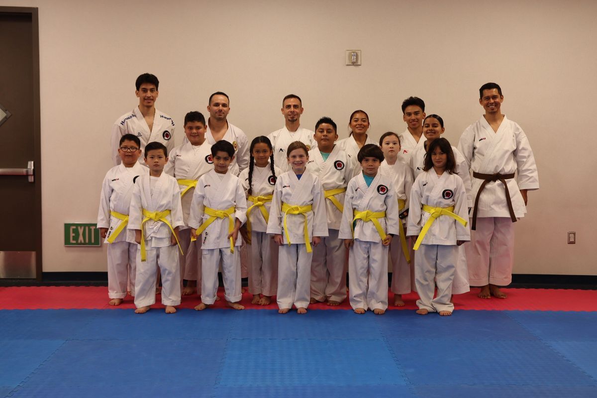 A group of children in karate uniforms are posing for a picture.