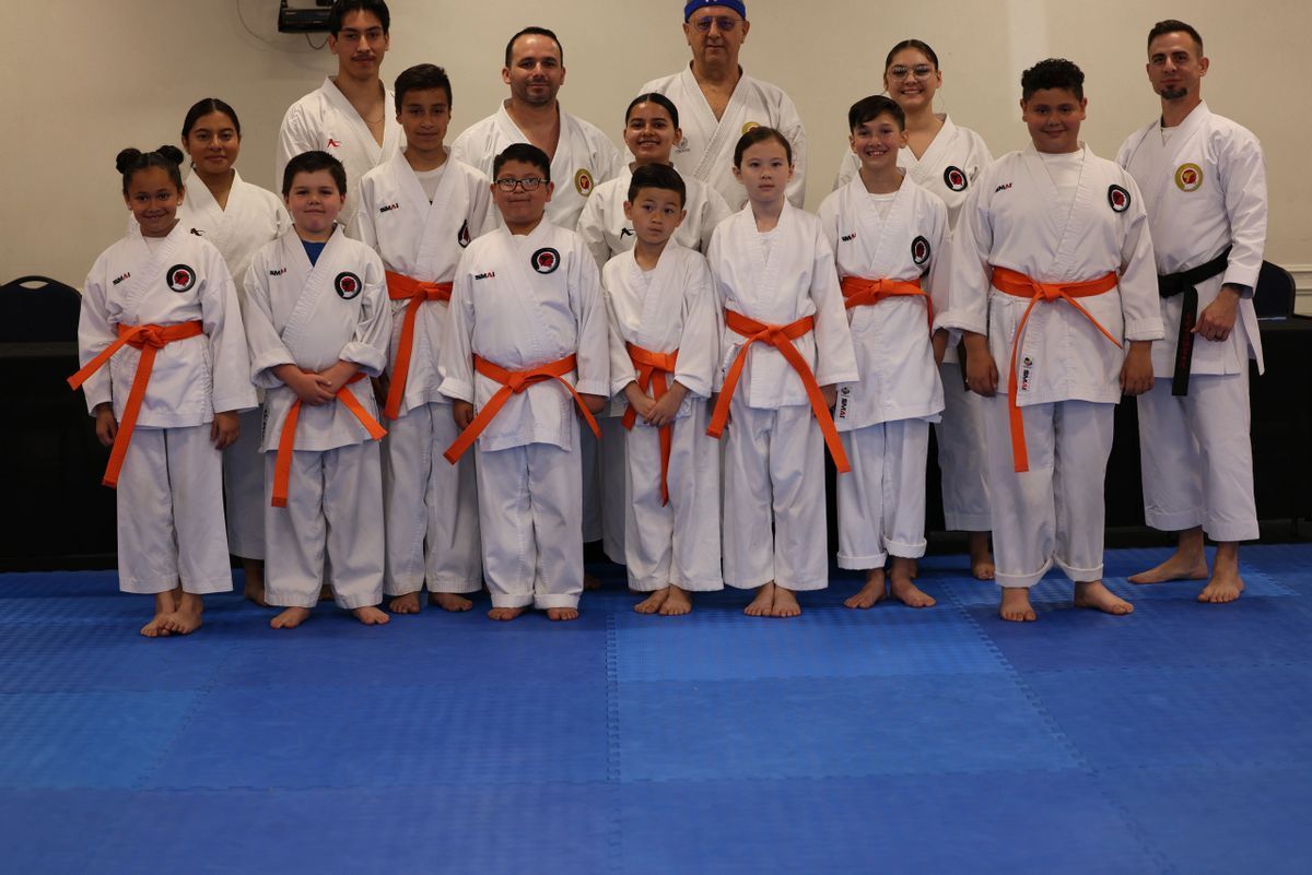 A group of people in karate uniforms are posing for a picture.
