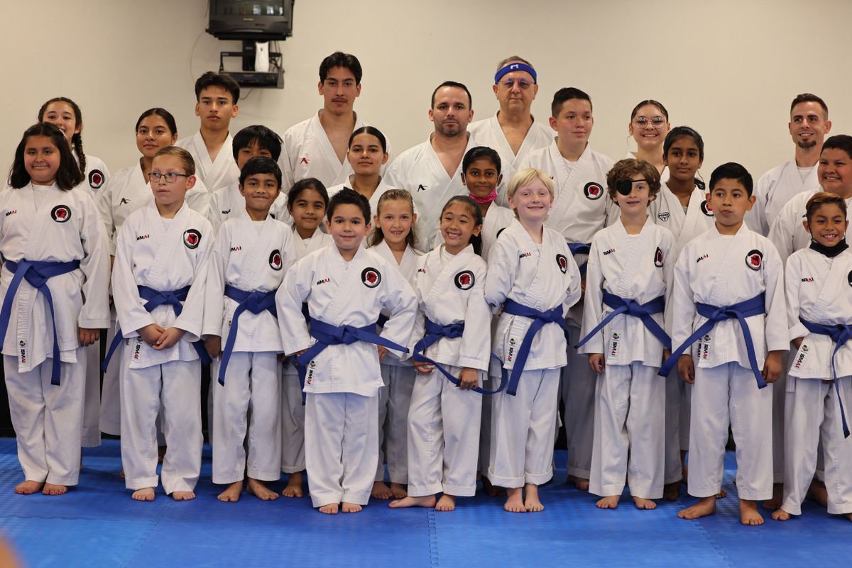 A group of people in karate uniforms are posing for a picture.