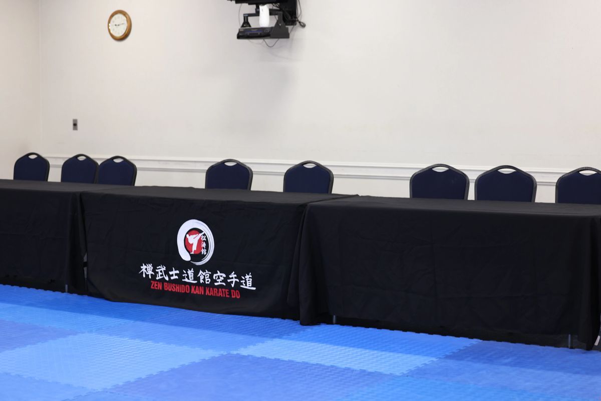 A room with a blue mat and black tables with chinese writing on them