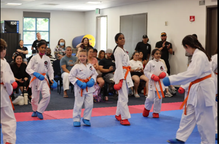 A group of young girls are practicing martial arts in front of a crowd