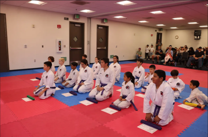 A group of kids are kneeling on a mat in a gym