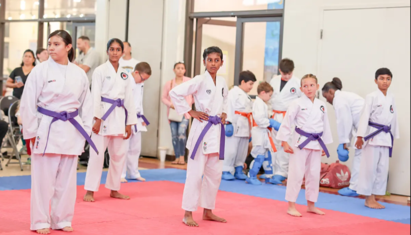 A group of young people are practicing karate in a gym.