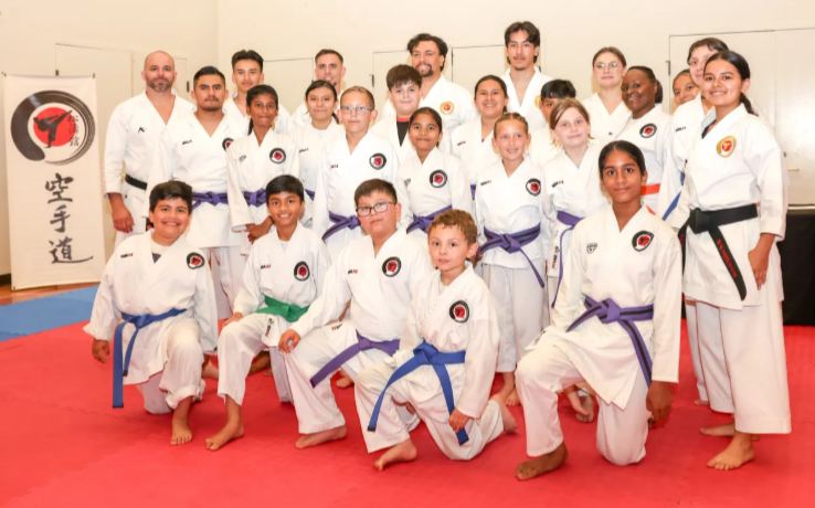 A group of people in karate uniforms are posing for a picture.