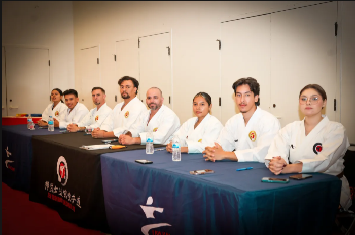 A group of people in karate uniforms are sitting at a table.