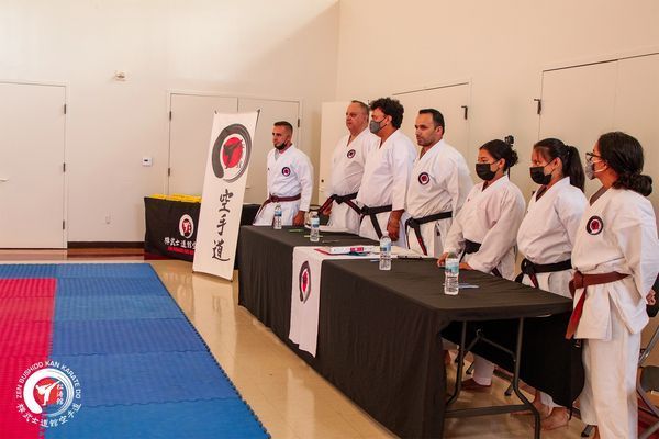 A group of people in karate uniforms are standing around a table.