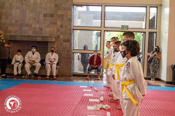 A group of children in karate uniforms are standing on a mat.