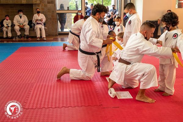 A group of people are practicing karate on a red mat.