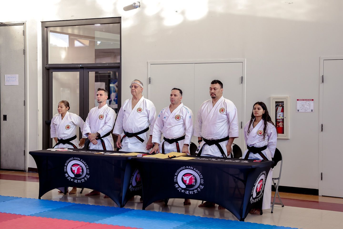 A group of people in karate uniforms are standing around a table.
