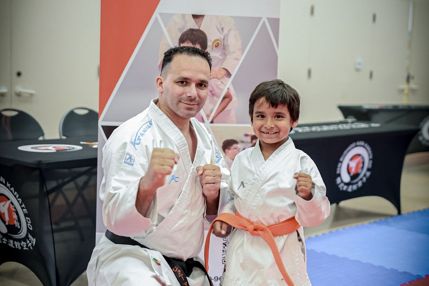 A man and a boy are posing for a picture in karate uniforms.