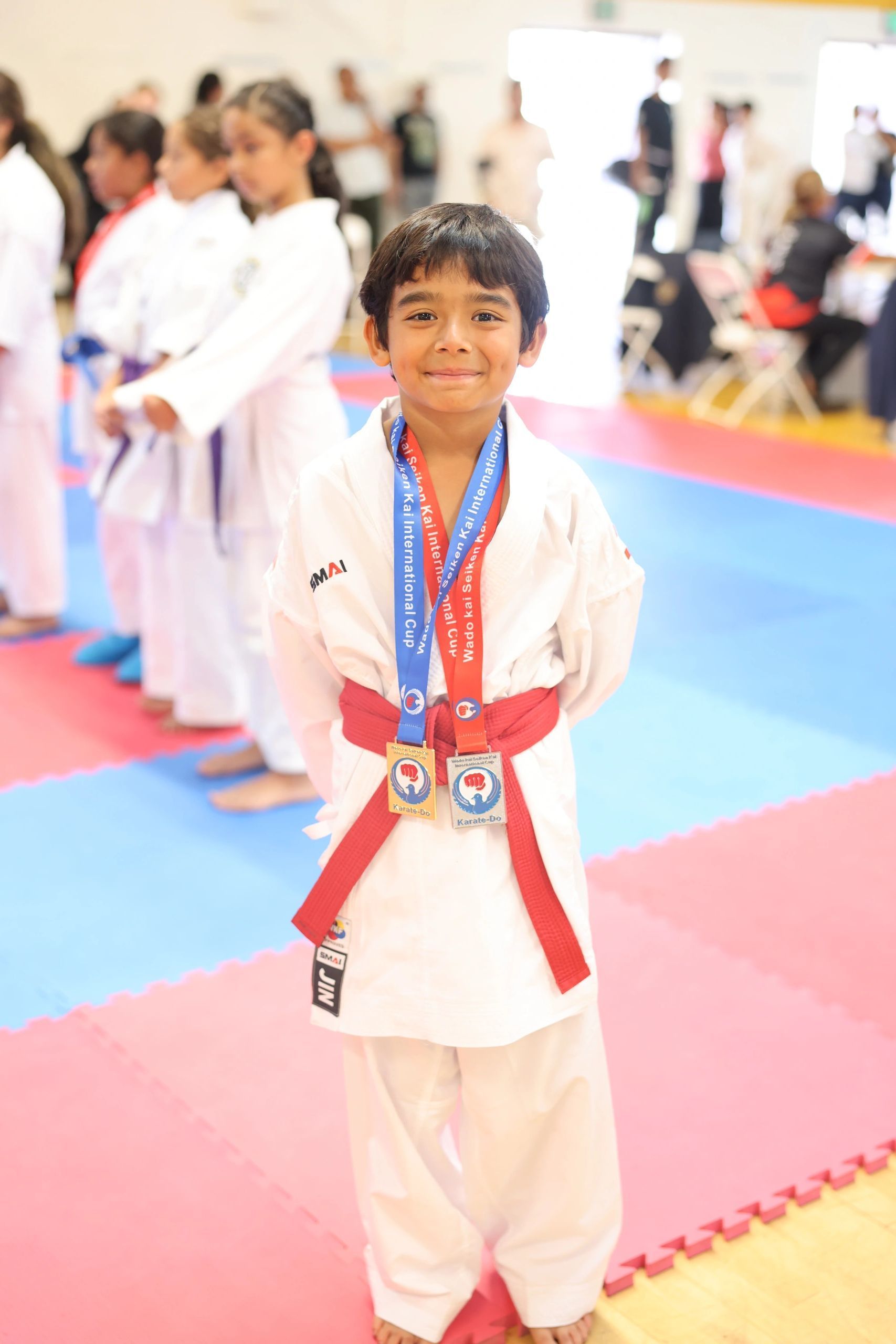 A young boy in a karate uniform is wearing a medal around his neck.