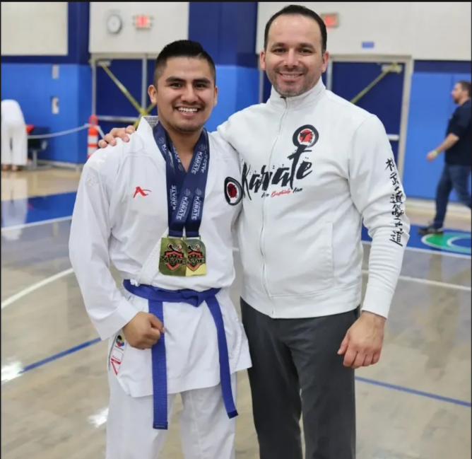 A man wearing a karate shirt poses with another man