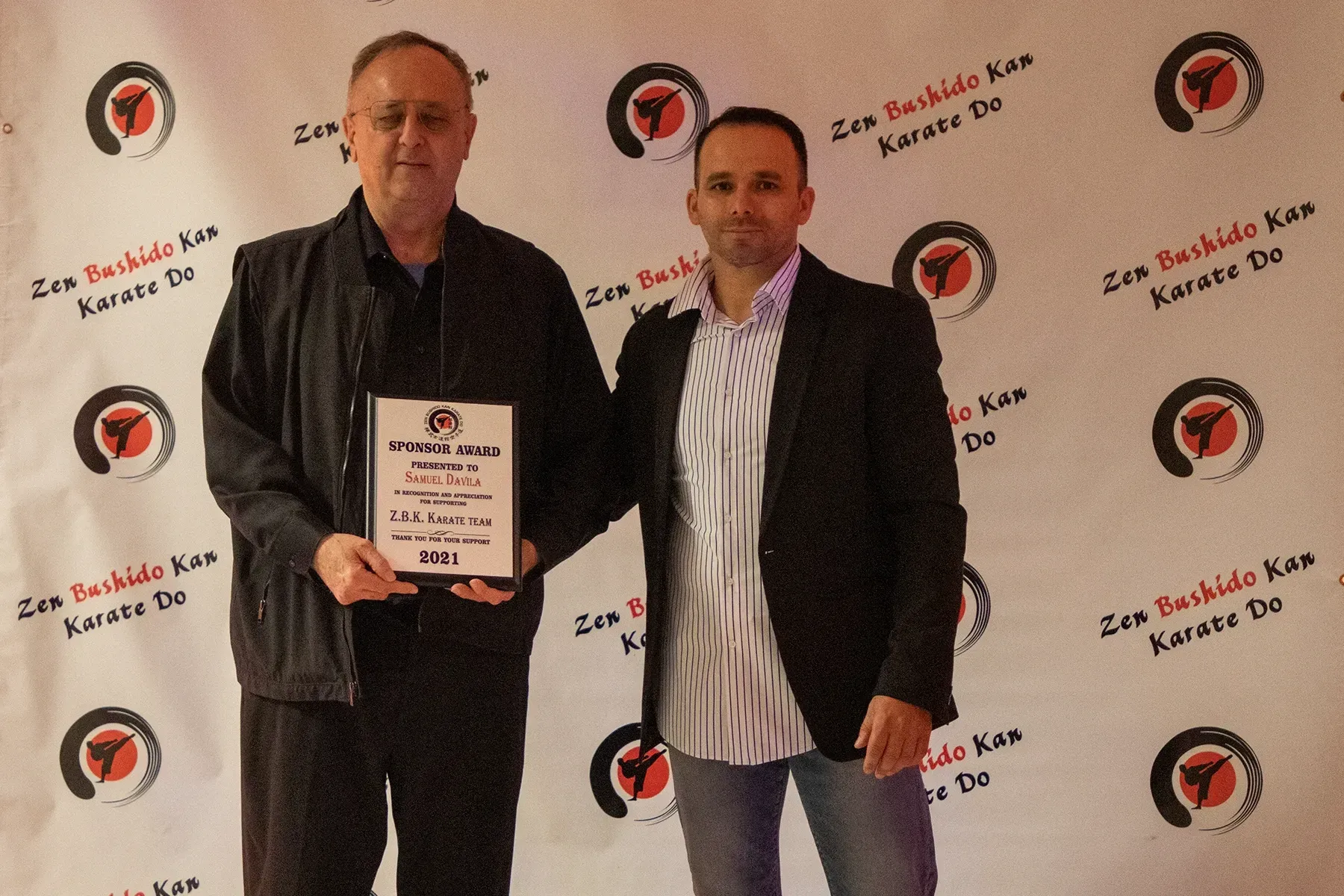 Two men standing in front of a wall that says karate on it