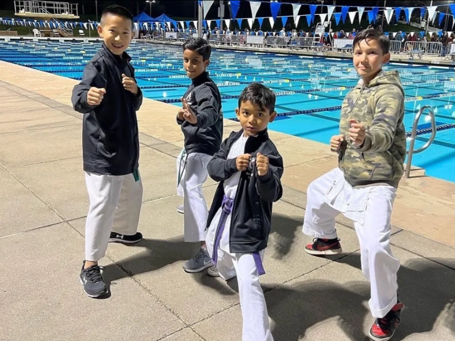 A group of young boys are practicing martial arts in front of a pool.