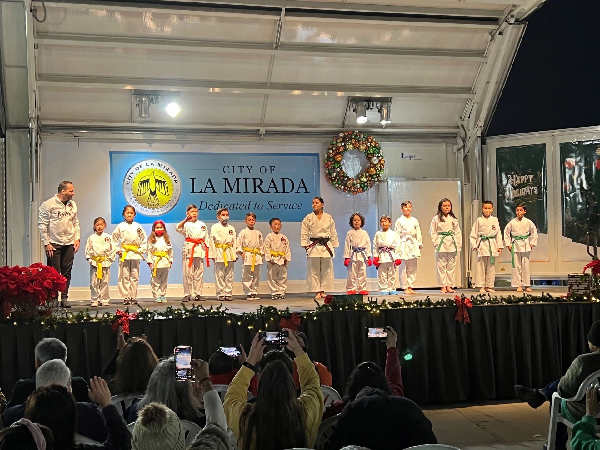 A group of children are standing on a stage in front of a crowd.