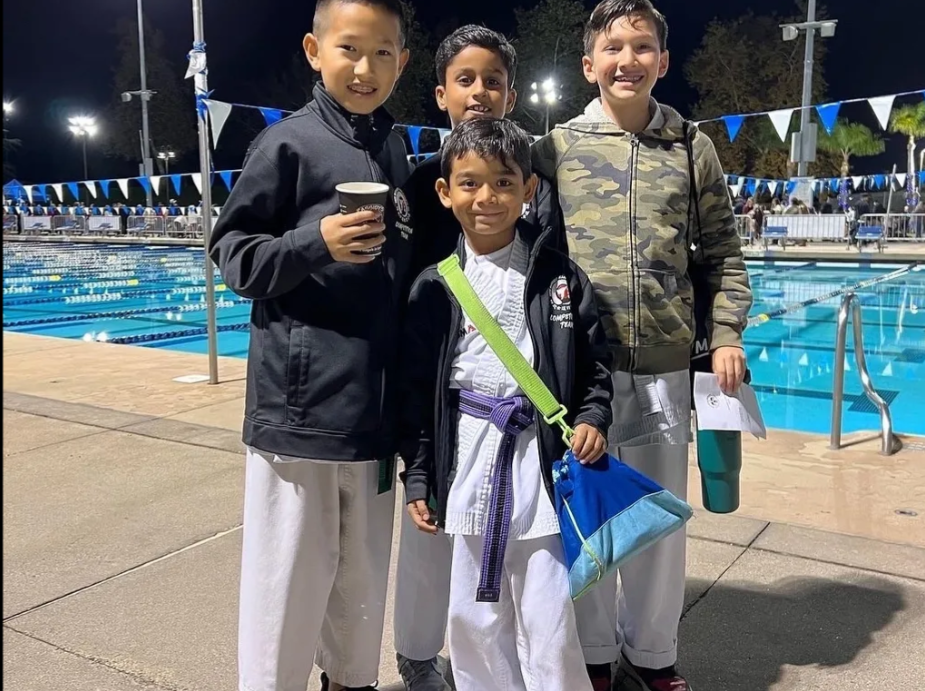 A group of young boys are posing for a picture in front of a swimming pool.