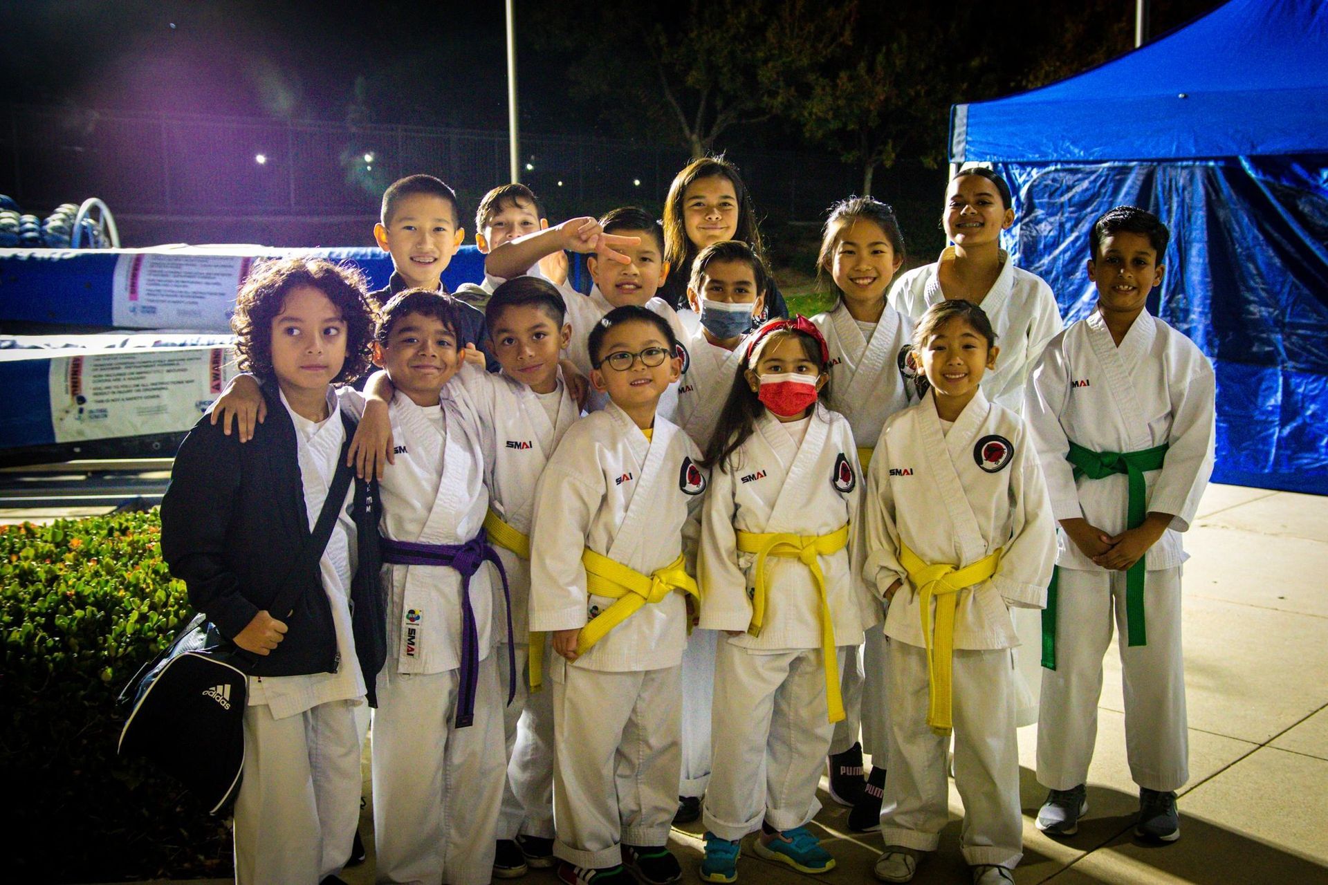 A group of children in karate uniforms are posing for a picture.