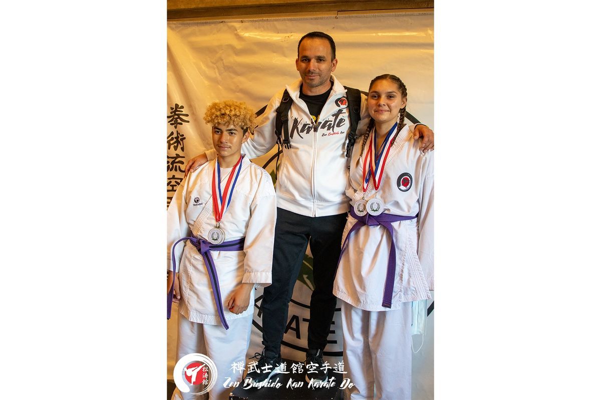 A man and two girls are standing next to each other in karate uniforms.