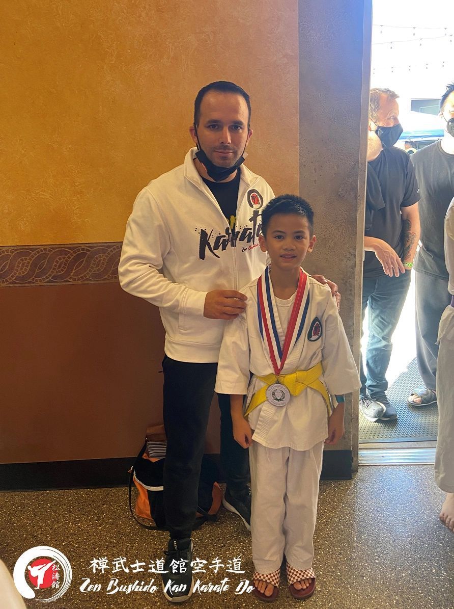 A man is standing next to a young boy wearing a medal.