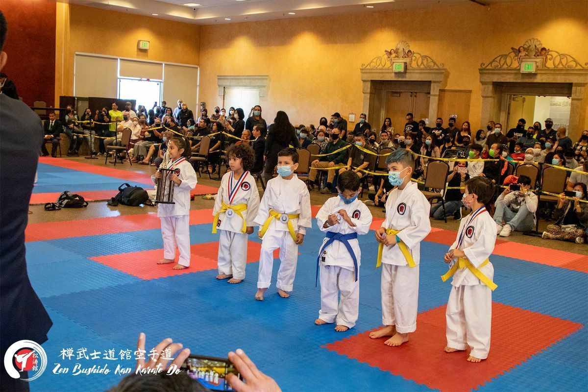 A group of young boys are standing on a karate mat in front of a crowd.