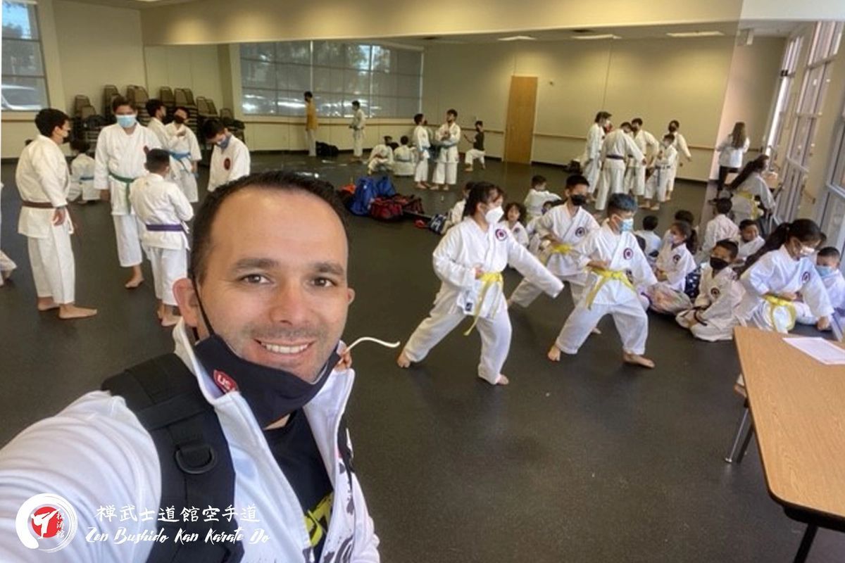 A man is taking a selfie in front of a group of people in karate uniforms.