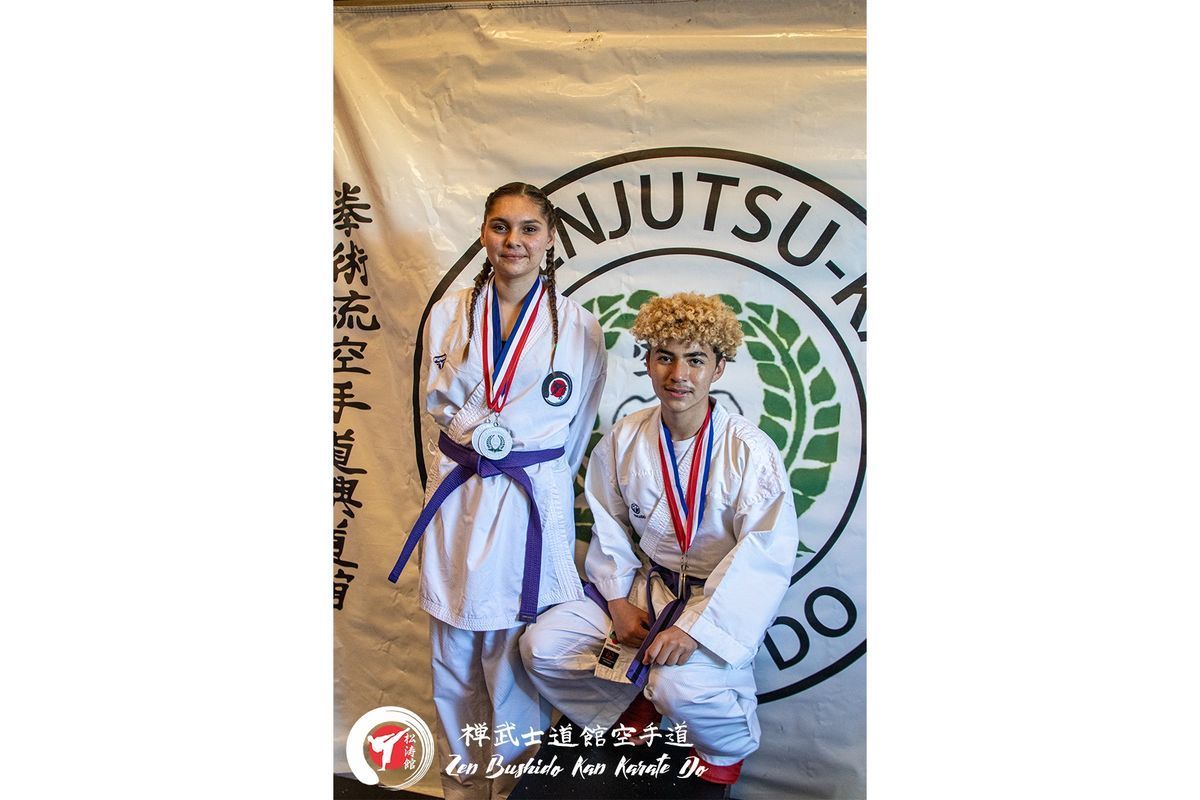 A man and a woman are posing for a picture in front of a banner.