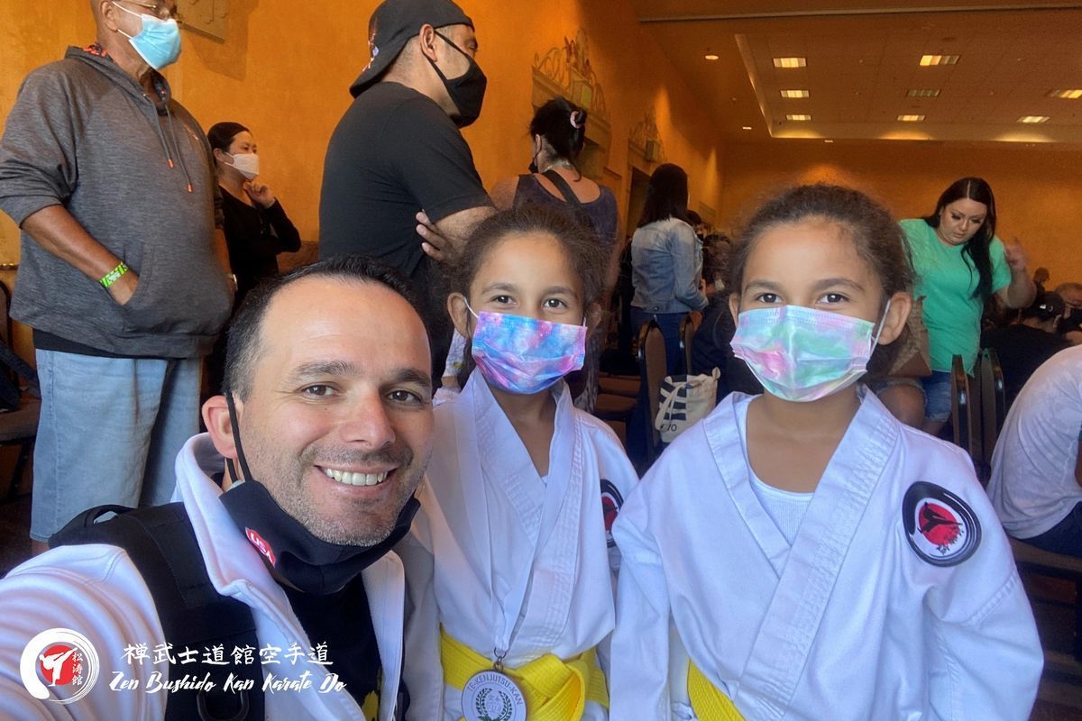 A man and two girls wearing masks are posing for a picture.