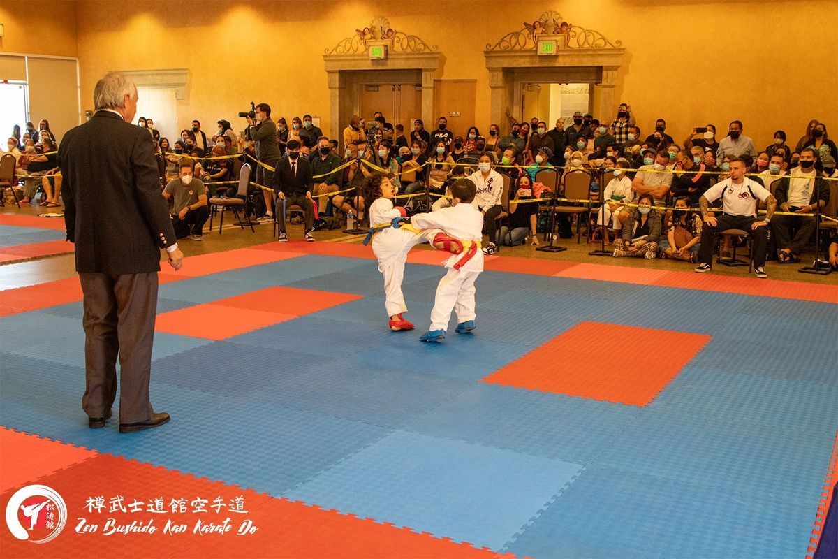 A referee watches two karate fighters on a mat