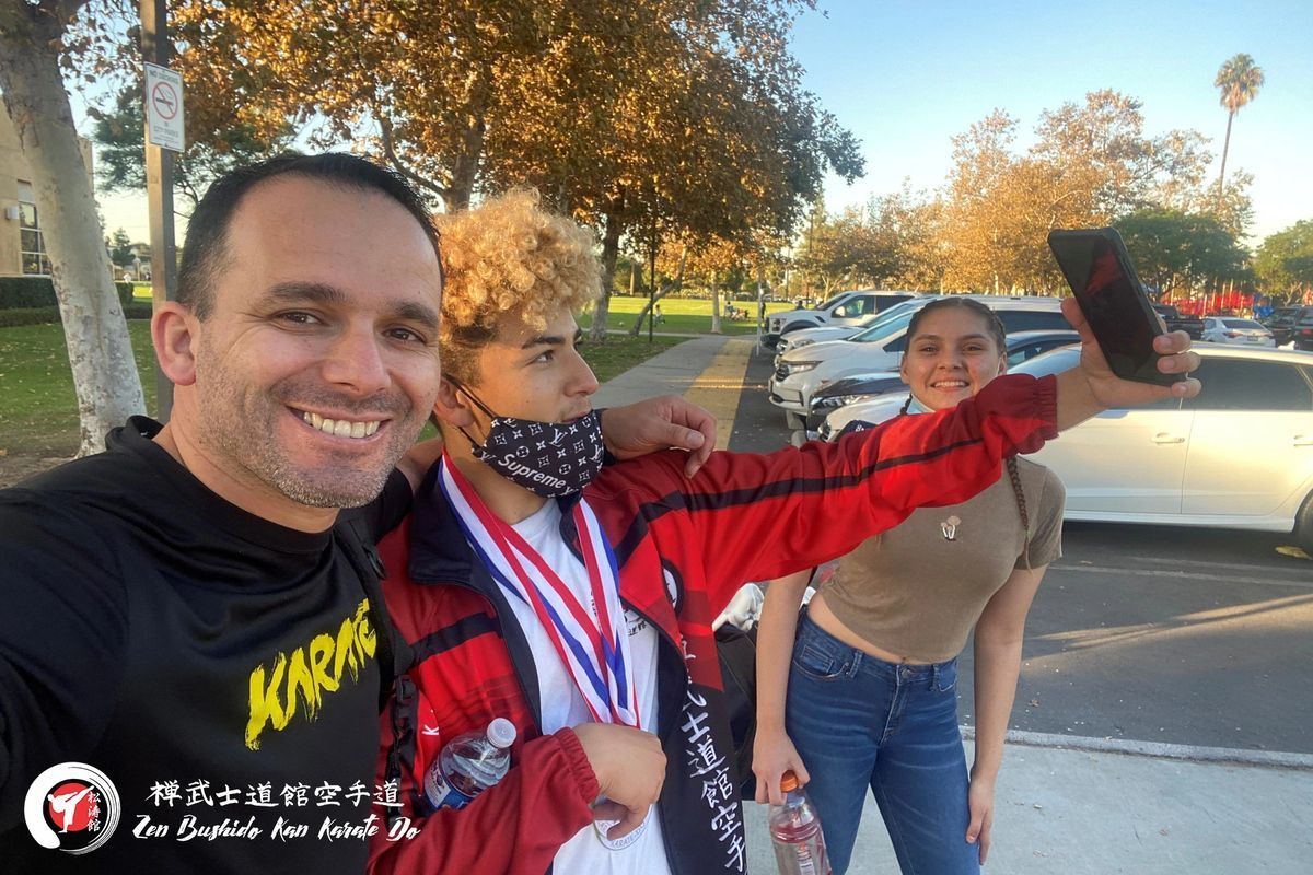 A man is taking a selfie with a young boy wearing a medal.