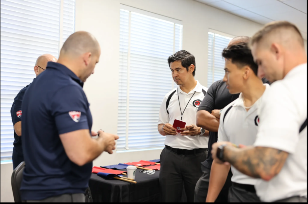 A group of men are standing in a room talking to each other