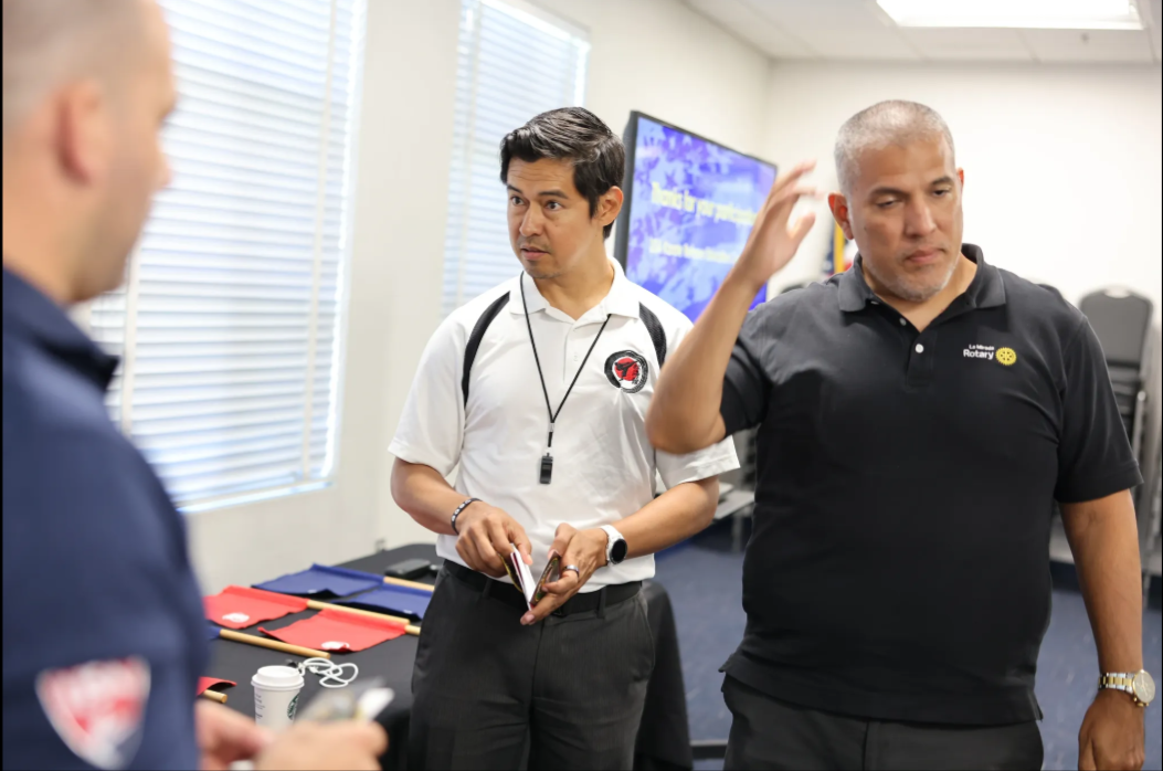 Three men are standing in a room talking to each other